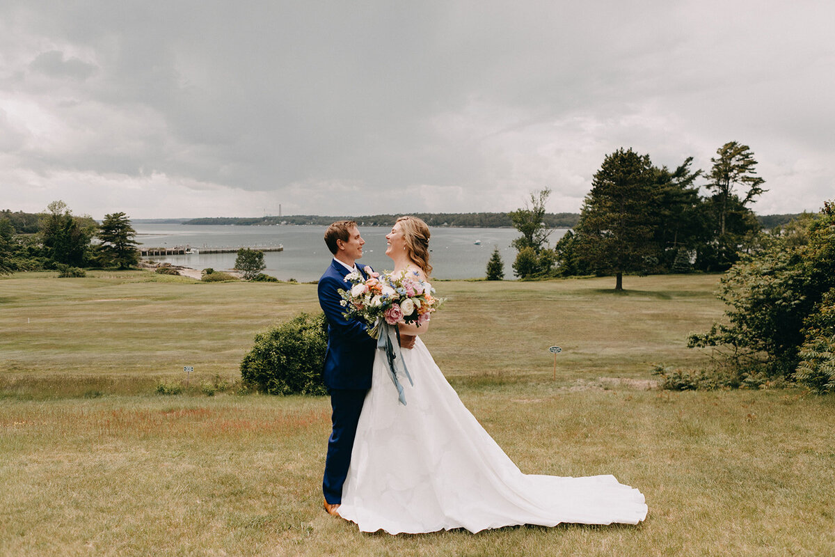 Bride and groom looking up at gray skies at Maine wedding