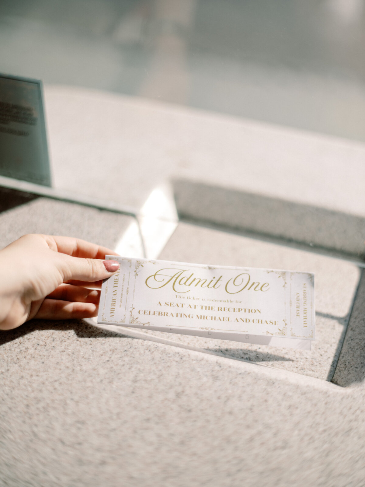A beautifully designed wedding invitation ticket held by a hand signifies the elegance of the upcoming celebration of Michael and Chase's union.