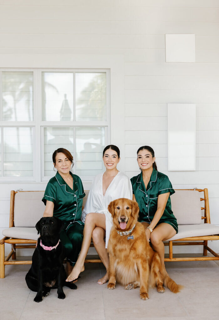 A joyful pre-wedding moment as the bride sits with her mother and sister in coordinating satin pajamas, surrounded by love and laughter. Captured by Florida Keys wedding photographer Claudia Amalia Photography.