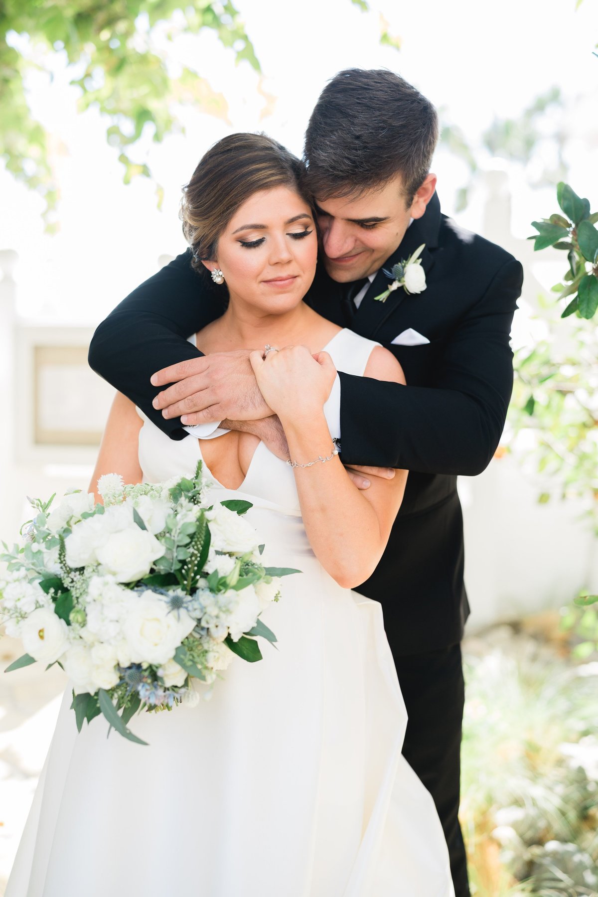groom hugging bride holding a bouquet