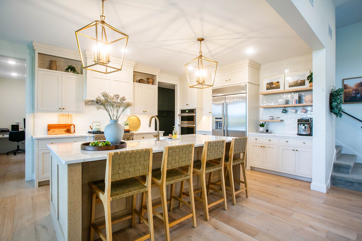 Open kitchen with white cabinets, large island, and quartz countertops in an Otsego custom home