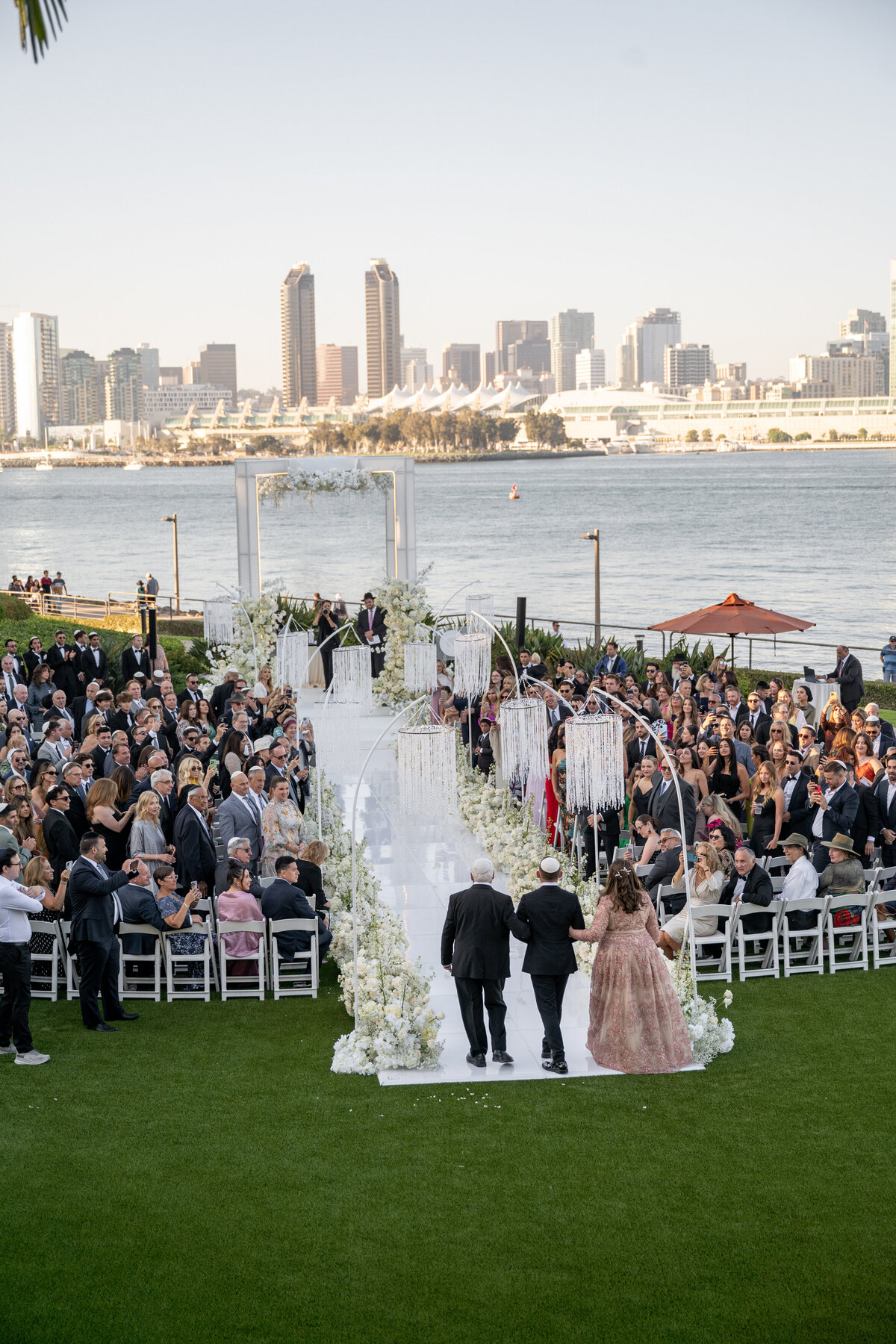 View looking down of a groom walking down an aisle with his parents