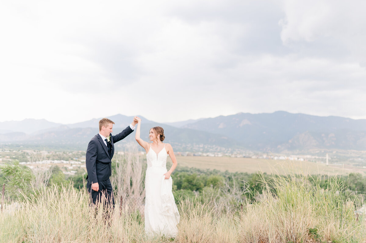 couple for colorado springs wedding photographer twirling in front of the mountain range