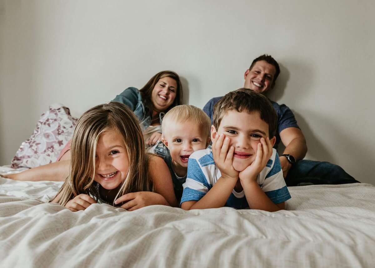 A Pittsburgh family photographer captures a family posing on a bed for a photo.