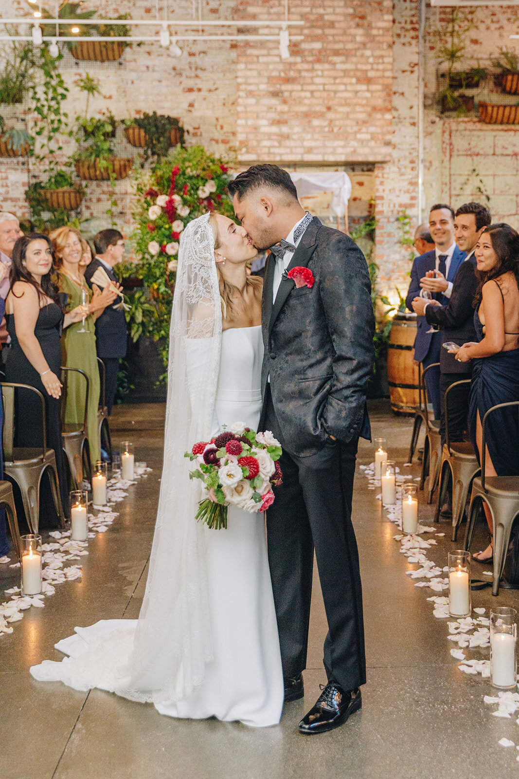 happy bride and groom kissing at the end of the aisle at brooklyn winery, with florals from Lucy's Flowers NYC