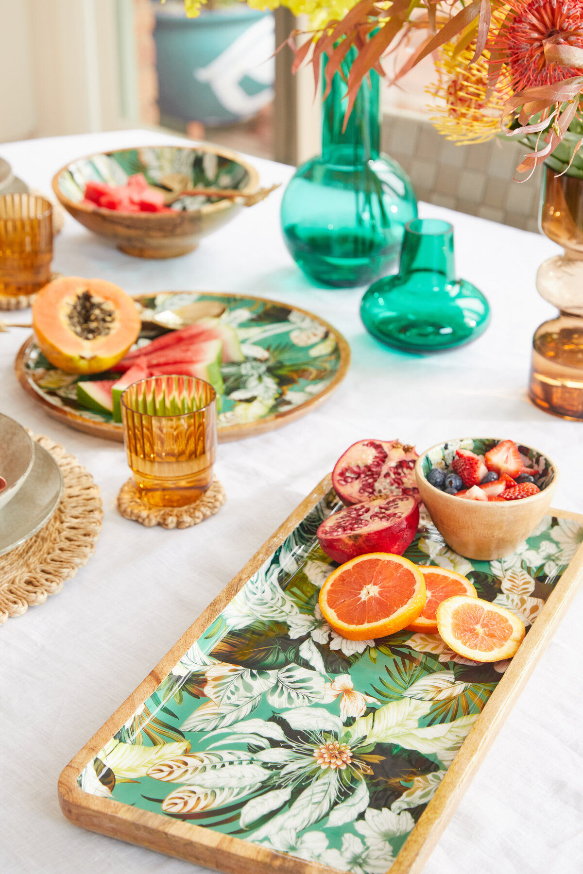 Summer table with tropical fruits, floral tableware and glass vases styled by interior designer Melbourne