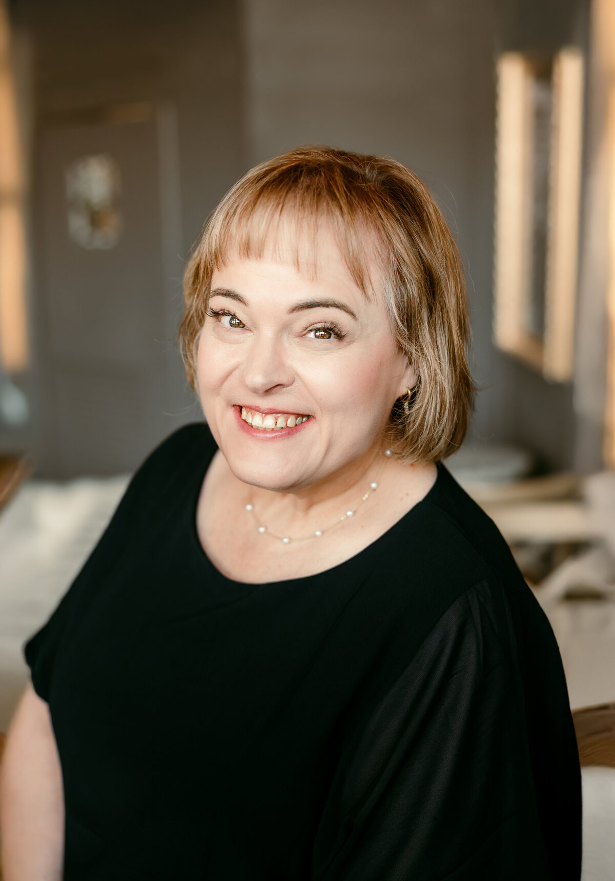 Natural light headshot of woman over 50 in black blouse for online dating profile