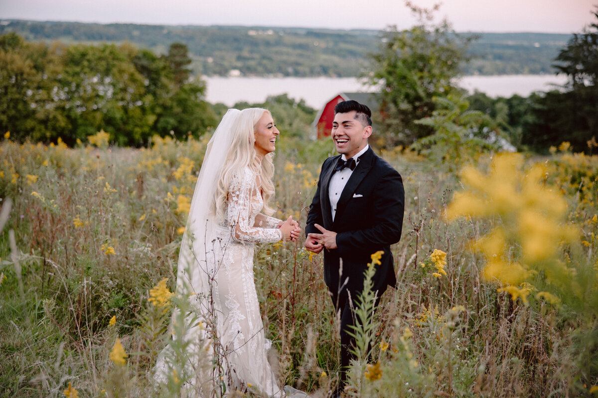 Groom helping bride with dress at outdoor wedding in Finger Lakes, Ny