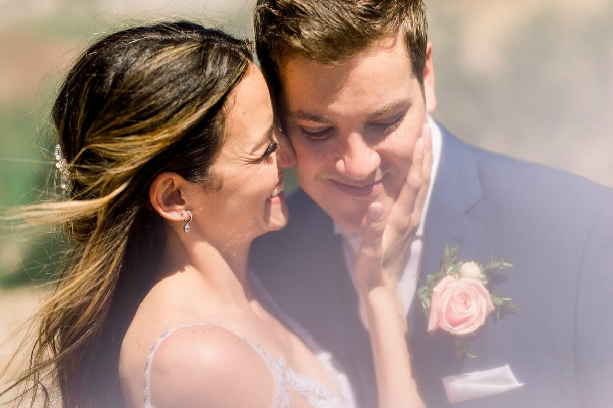 Bride-laughing-and-holding-grooms-face-during-their-helicopter-elopement