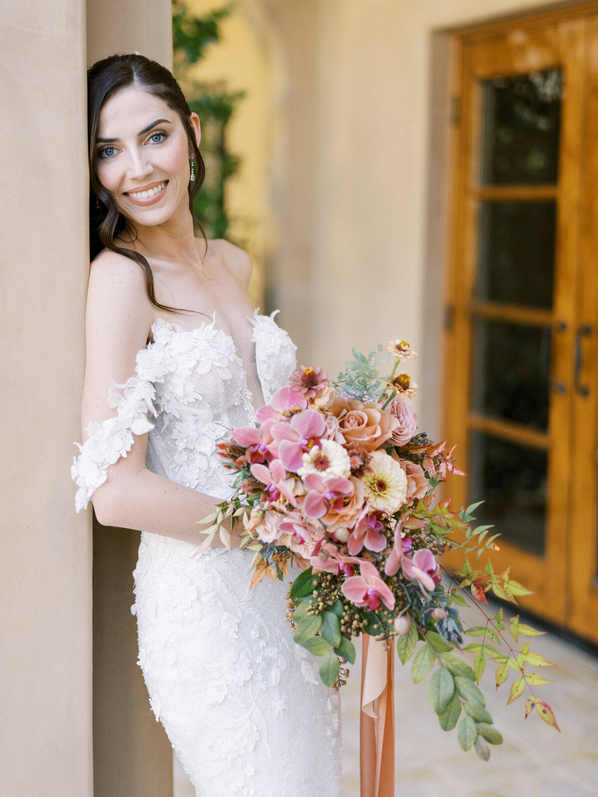 Bridal beauty in full bloom—lace gown, radiant smile, and a cascading bouquet of romantic florals at Allegretto Vineyard.
