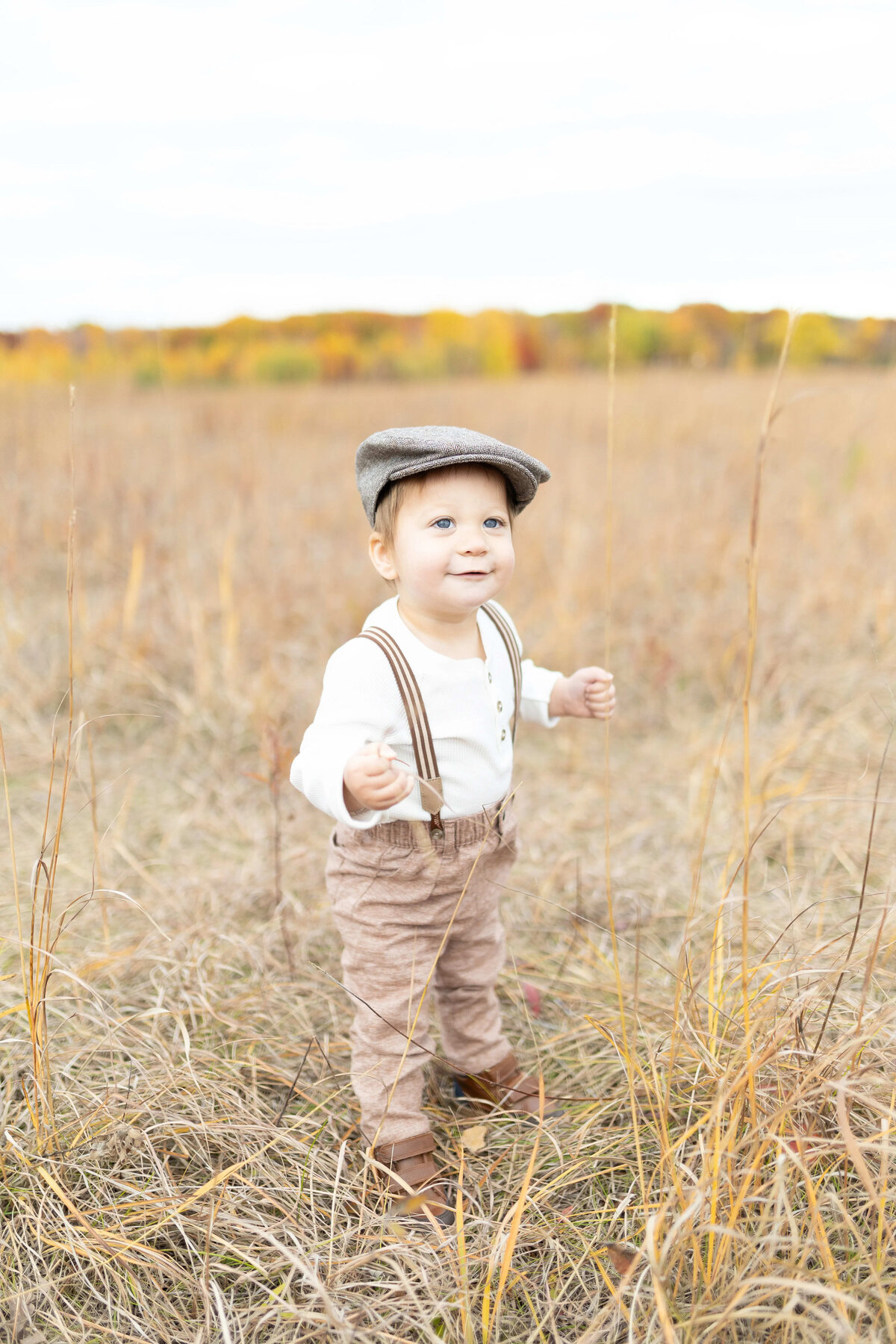 Toddler boy in suspenders and cap in field - fall outdoor milestone session Maple Grove