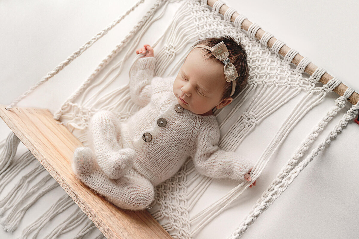 Baby girl asleep at her Greater Toronto  newborn  photography session by Tamara Danielle on a macrame swing.