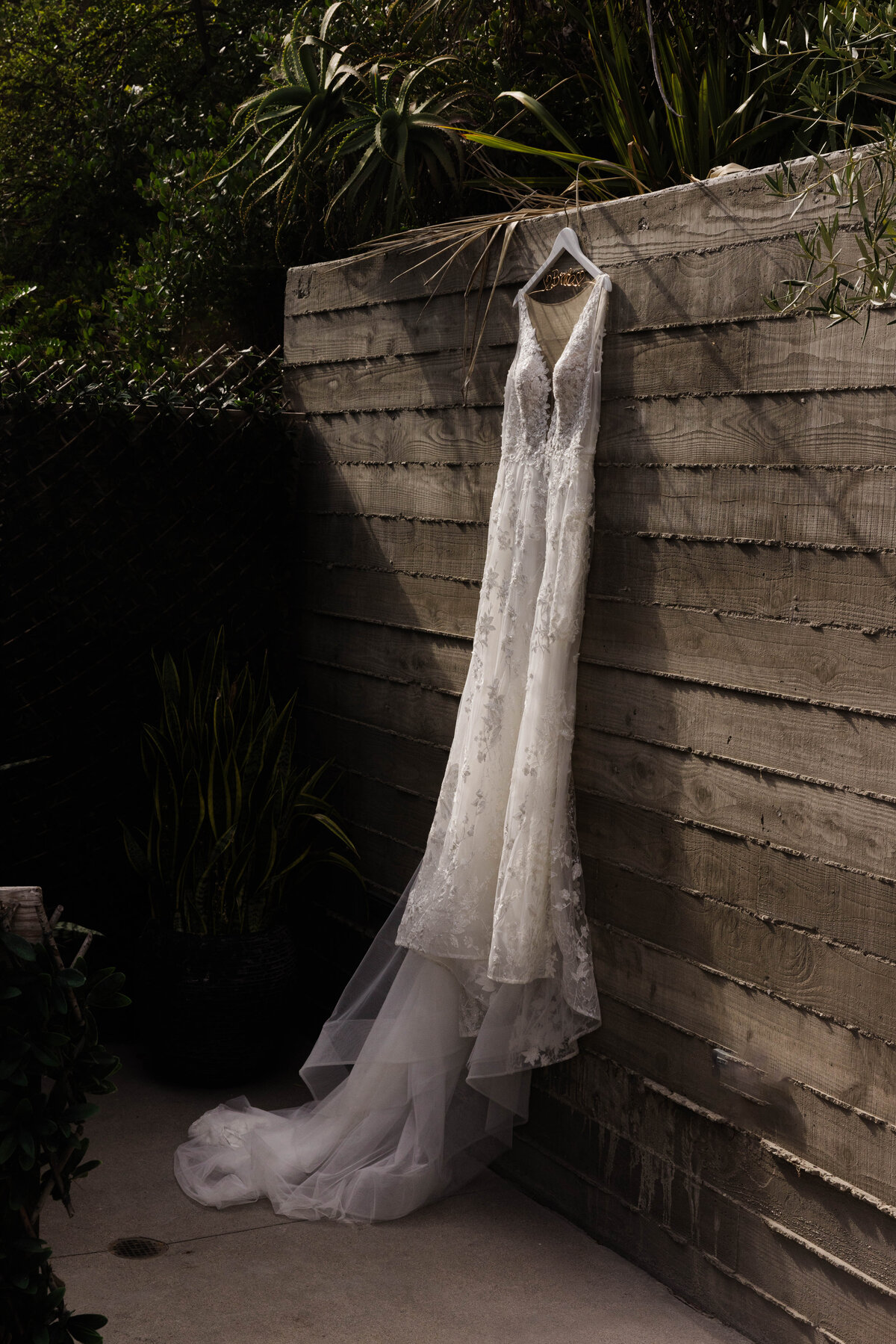 wedding dress hanging from a wooden fence