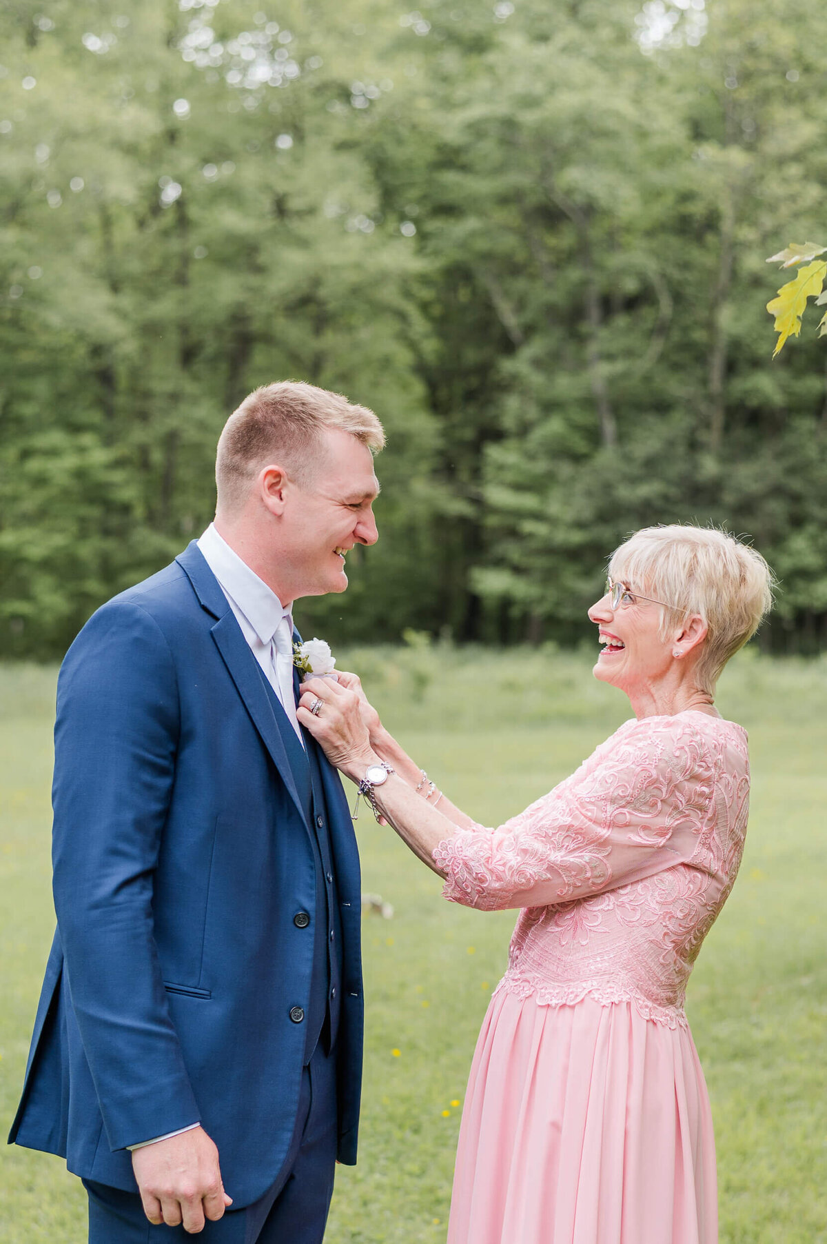 Mother of the groom pins his boutonniere before the ceremony, captured by a timeless Pittsburgh wedding photographer.