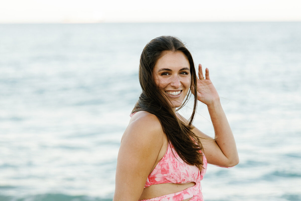 Rebecca smiles radiantly while standing by the shoreline during her romantic engagement session at Marriott Hotel Fort Lauderdale, captured by Claudia Amalia Engagement Photography.