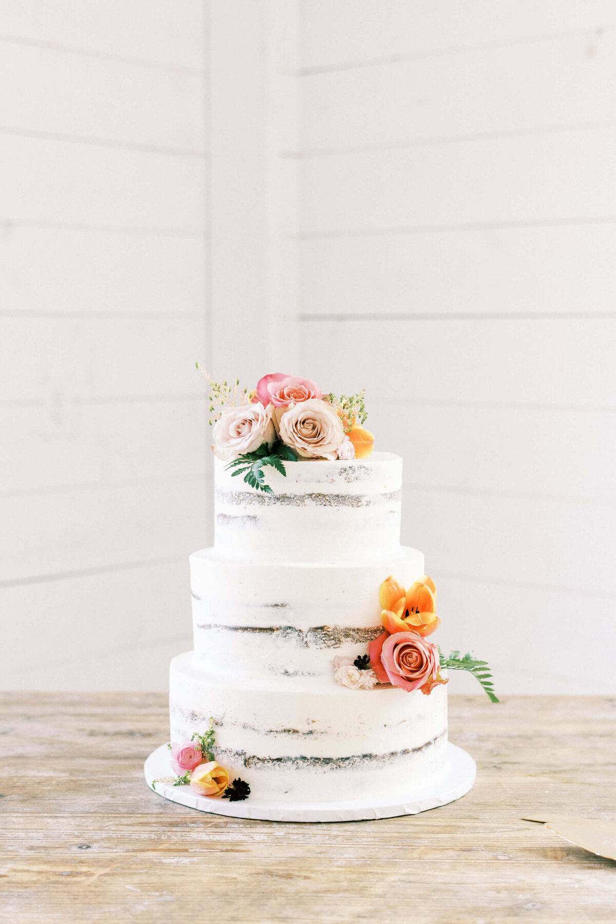 Naked wedding cake with roses at barn venue in North Texas
