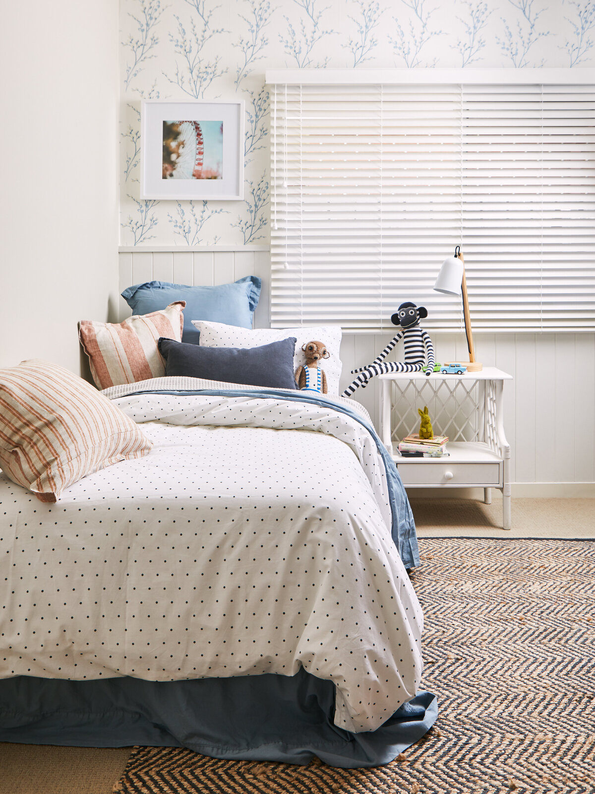 Eynesbury children’s room styled with twin beds, polka dot bedding, playful cushions and a soft blue wallpaper backdrop.
