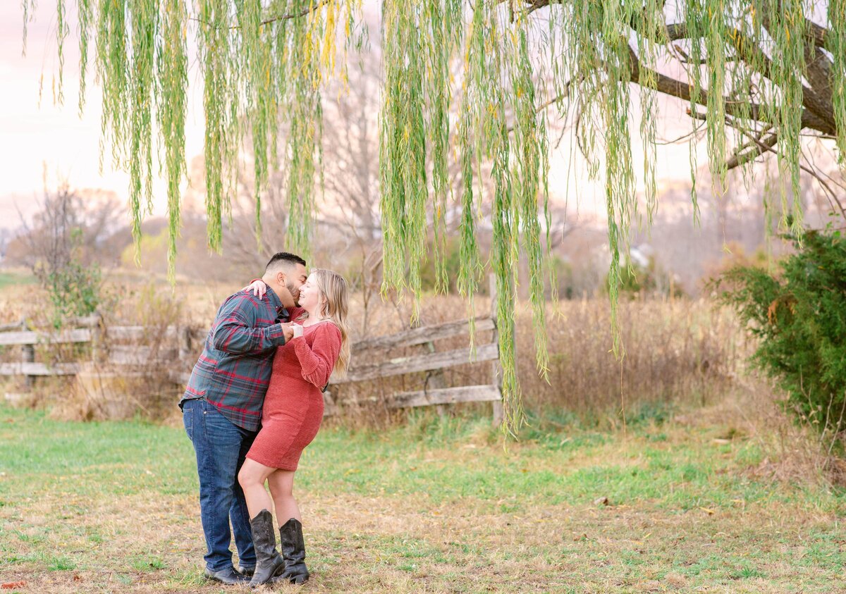 Couple leaning back for a dip during Engagement Photos under a willow tree in Fredericksburg, Virginia. Captured by Bethany Aubre Photography.