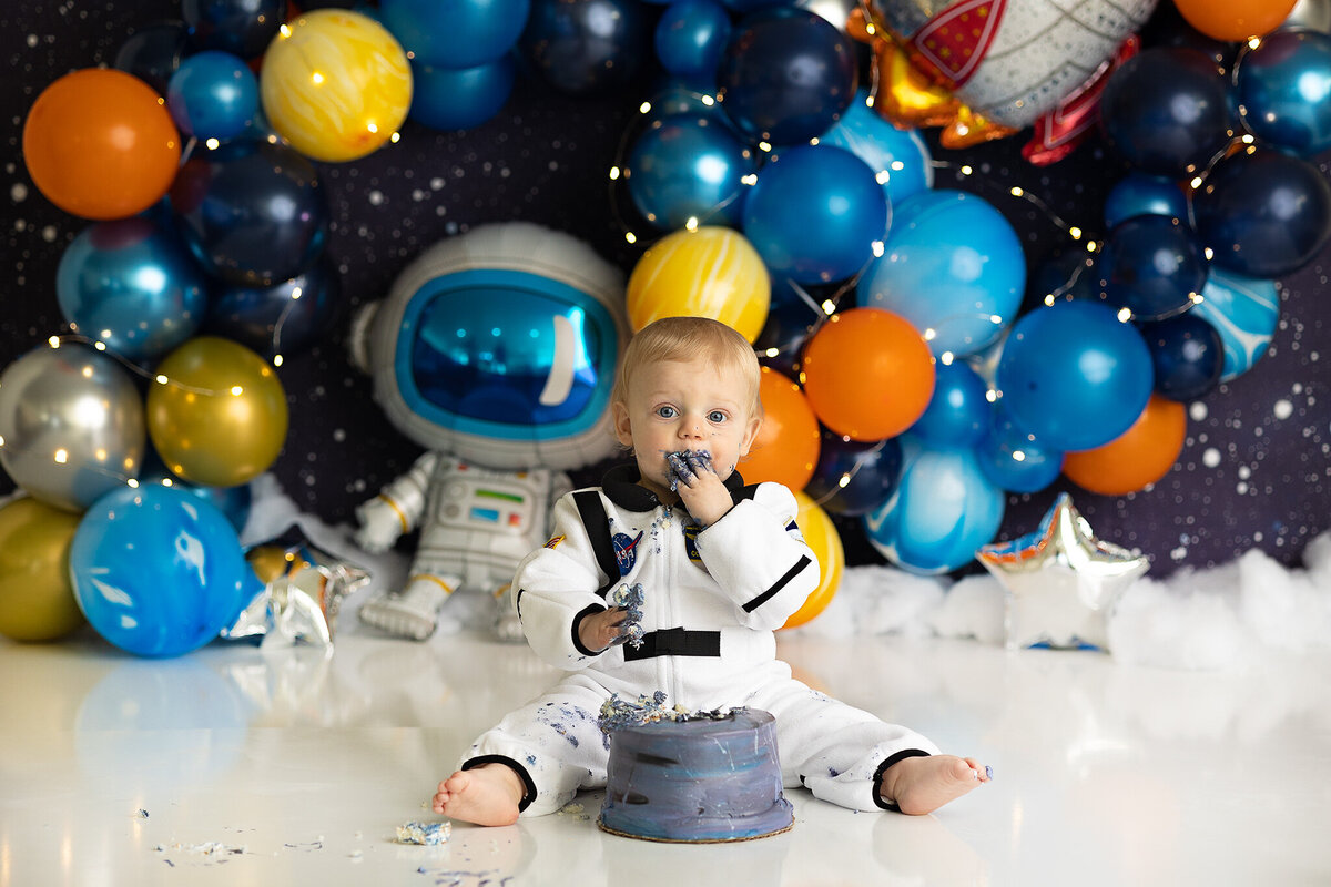dayton-and-columbus-ohio-cake-smash-photographer-baby-boy-in-astronaut-outfit-and-space-themed-backdrop-with-matching-cake-amanda-estep-photography