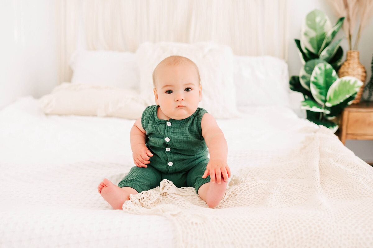 baby boy holding toes sitting on bed captured by Branson MO baby photographer Jessica Kennedy of The XO Photography during childrens milestone session