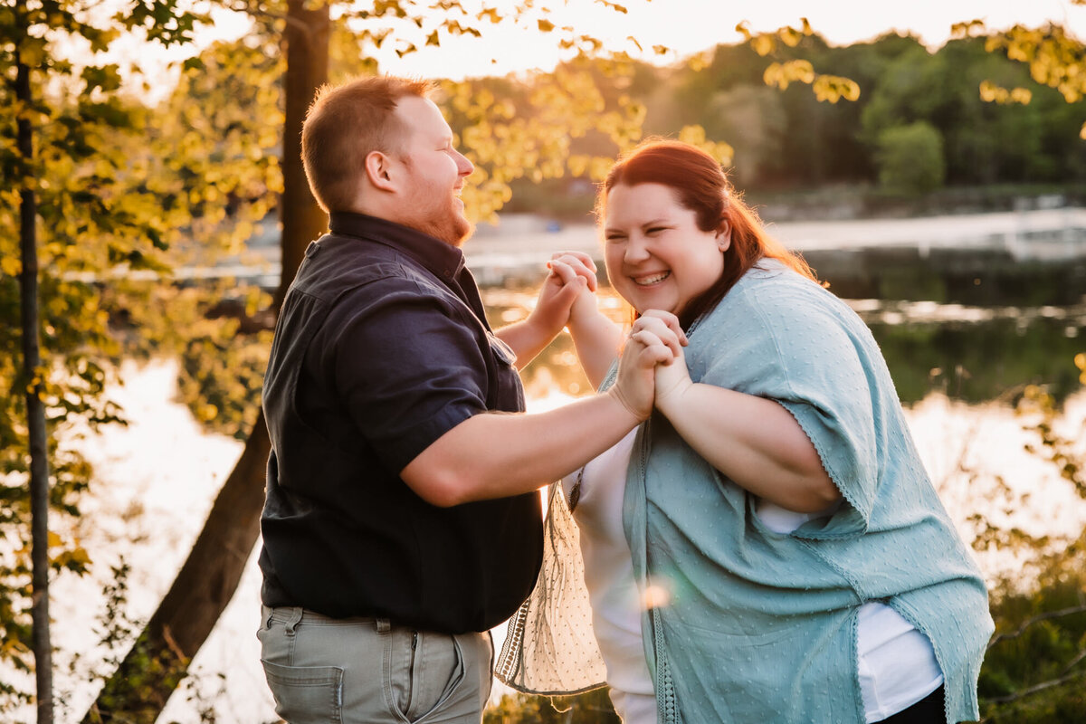 man and woman hold hands while laughing hard at sunset in Menomonee Park