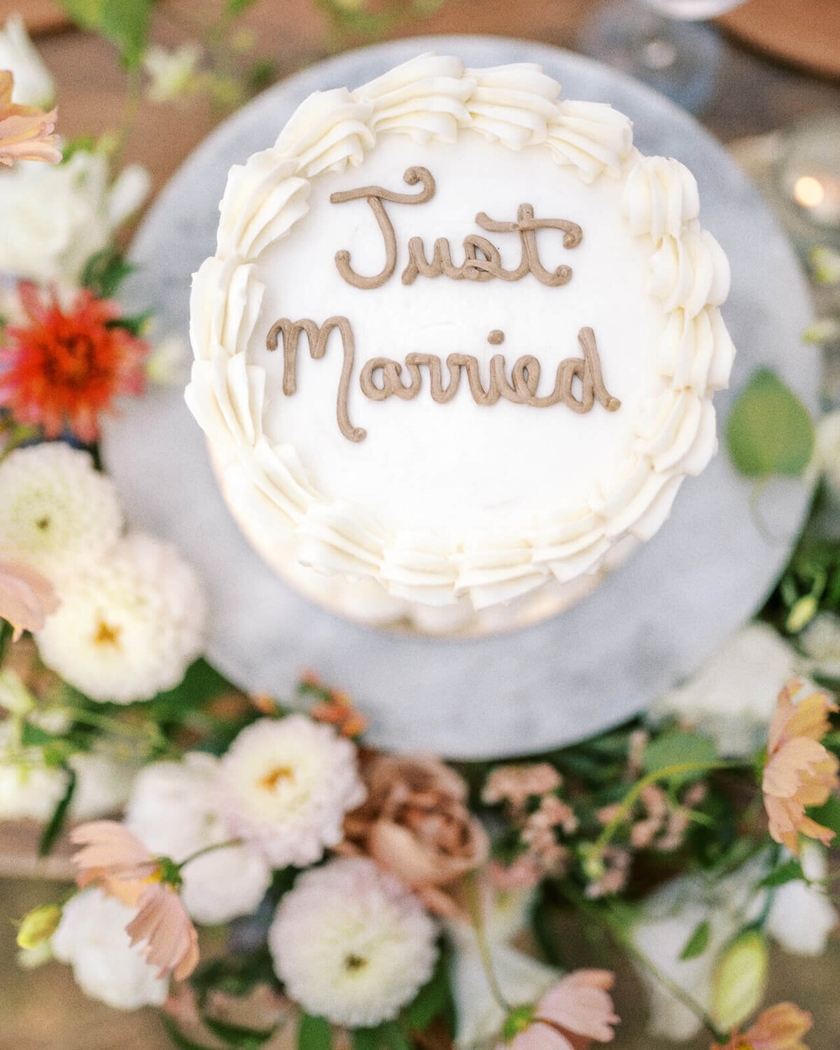 A wedding cake that says Just Married surrounded by flowers.