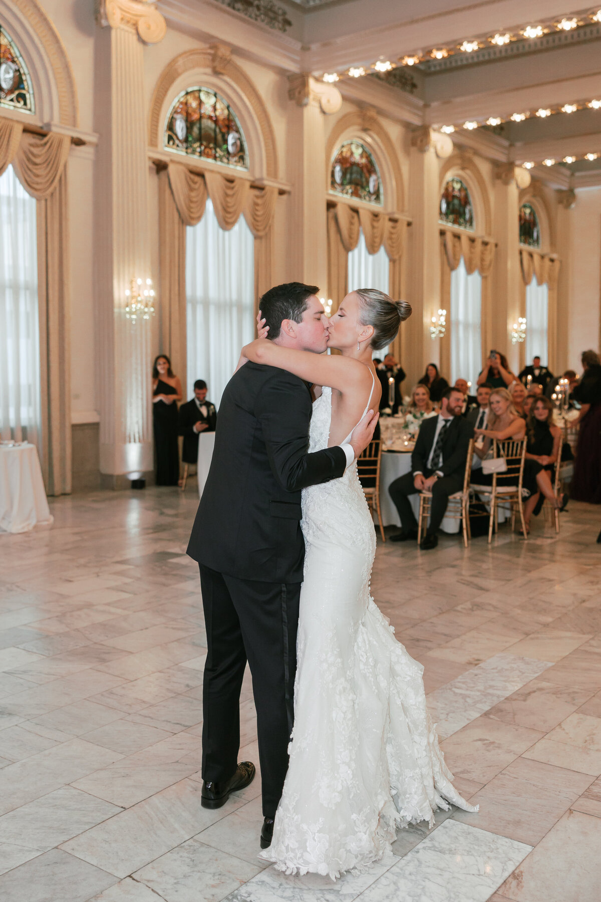 Bride and groom kiss during first dance in grand ballroom by Philadelphia wedding photographer.