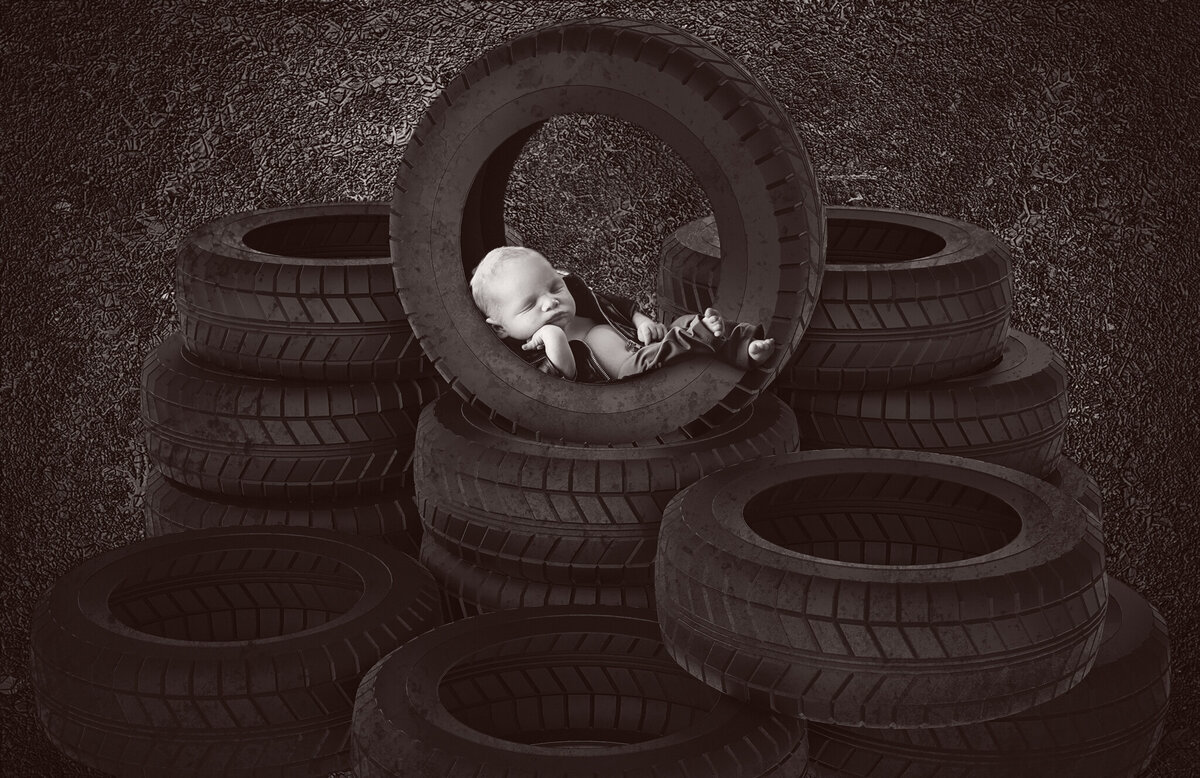 "Rustic newborn portrait featuring a baby nestled in a stack of tires, captured in Overland Park, Kansas. Perfect for families seeking unique and creative newborn photography with an industrial edge in the Kansas City area."