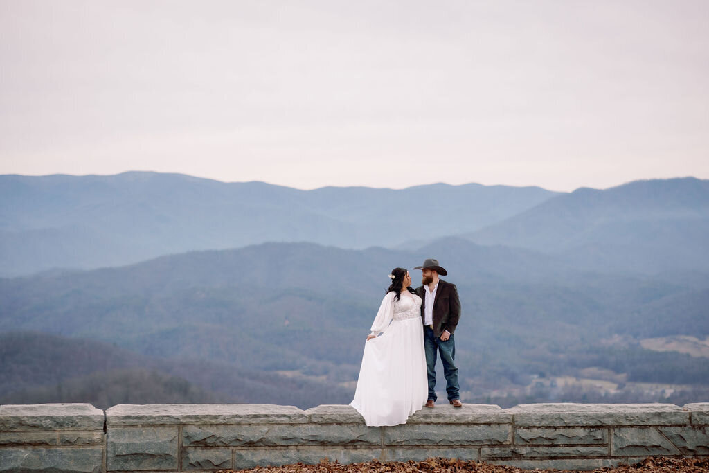 winter elopement with bride and groom at foothills parkway Tennessee standing on a stone wall while looking at one another