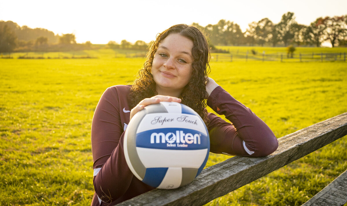 Senior portrait of a young woman posing with a volleyball