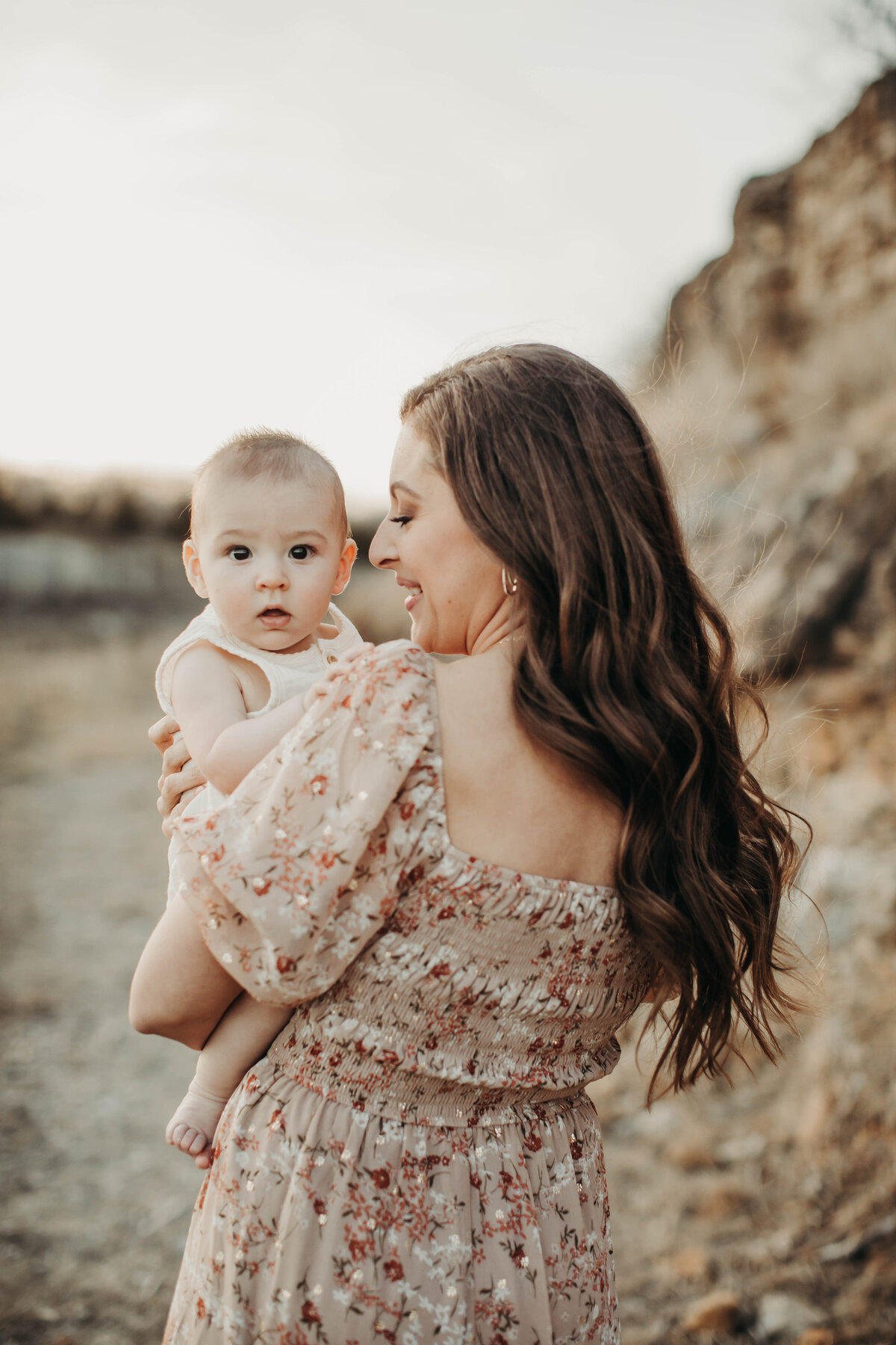 Mom holding her 6-month-old baby boy close, bathed in golden hour light.