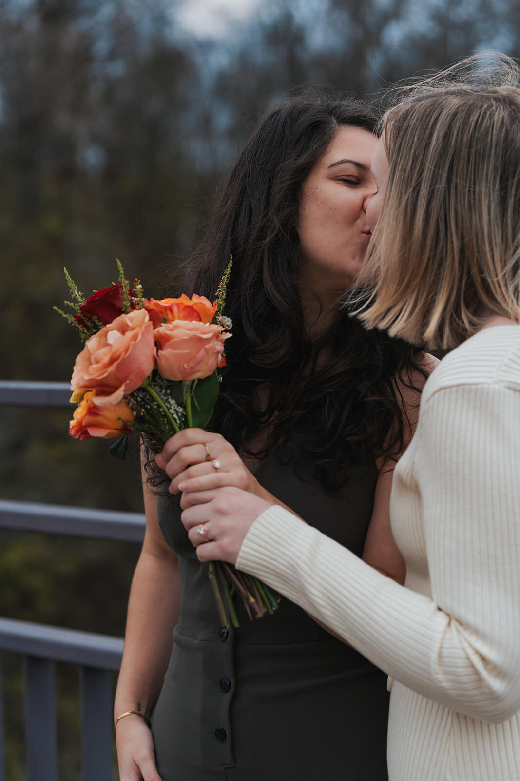 Women kiss while holding their elopement bouquet 