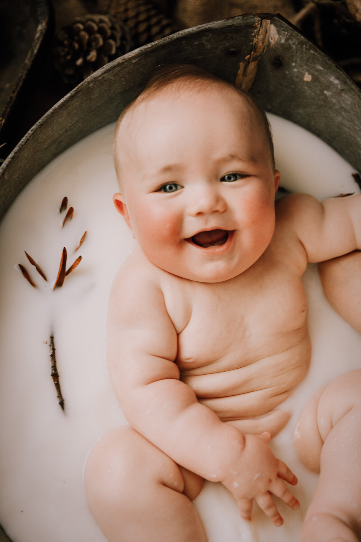 chubby little baby boy laughing in his milkbath