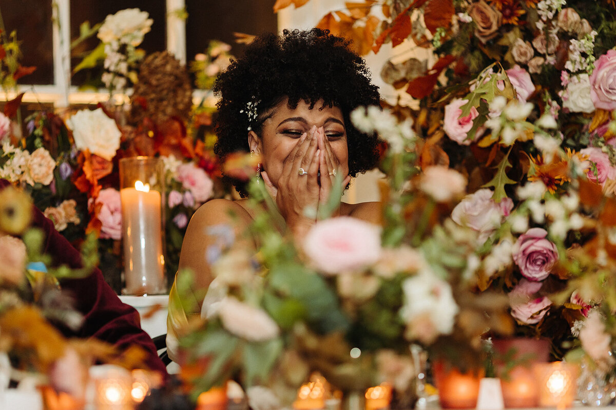Lush growing florals surround the couple at this autumnal wedding’s sweetheart table composed of roses, ranunculus, lisianthus, dried hydrangea, delphinium, copper beech, and fall foliage creating hues of dusty rose, burgundy, mauve, copper, terra cotta, and hints of lavender. Design by Rosemary and Finch in Nashville, TN.