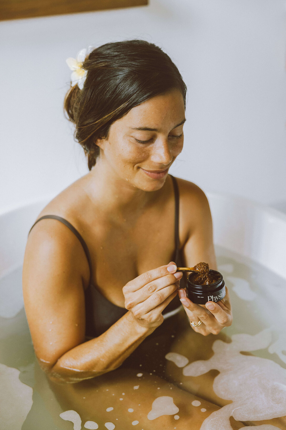 Skin care brand photography of woman holding skincare jar in luxurious bath
