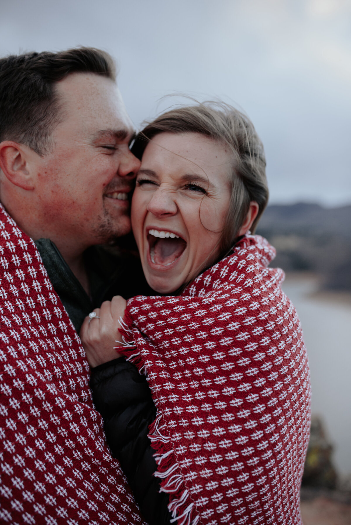 colorado couple wrapped in cute picnic blanket with horsetooth reservoir in the background for their couples professional photoshoot