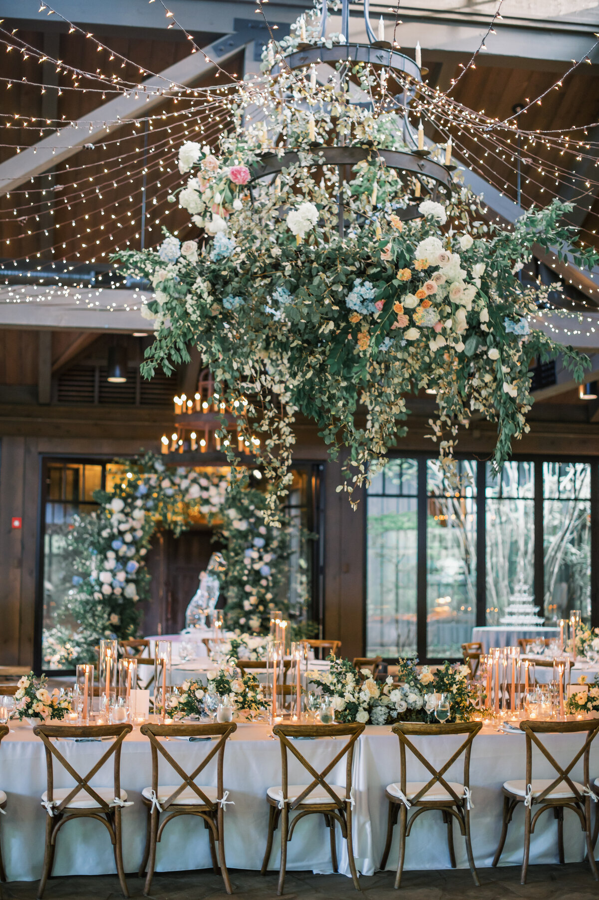 Wedding reception tables lined with candlelight beneath a floral chandelier and twinkle lights at Old Edwards Inn in Highlands, North Carolina.
