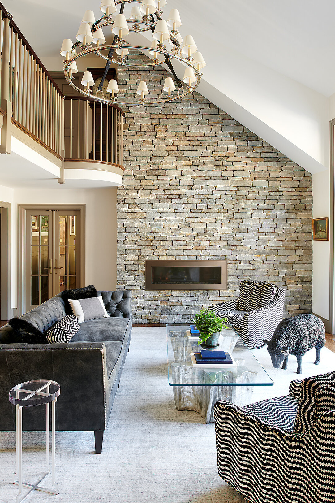 high ceiling living room with candle chandelier and brick accent wall