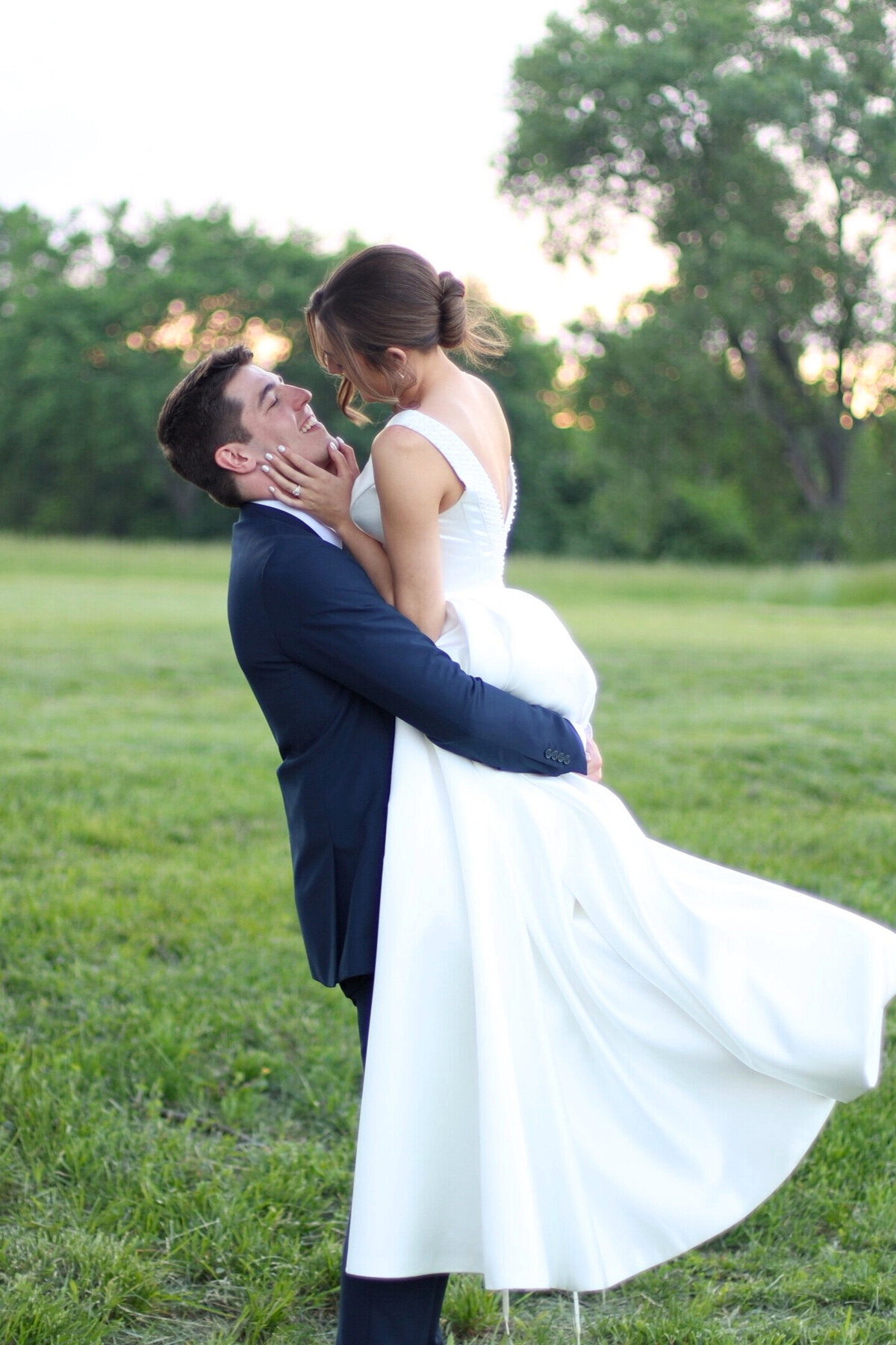 Groom picking up bride and spinning her at sunset at Fireflies Farm
