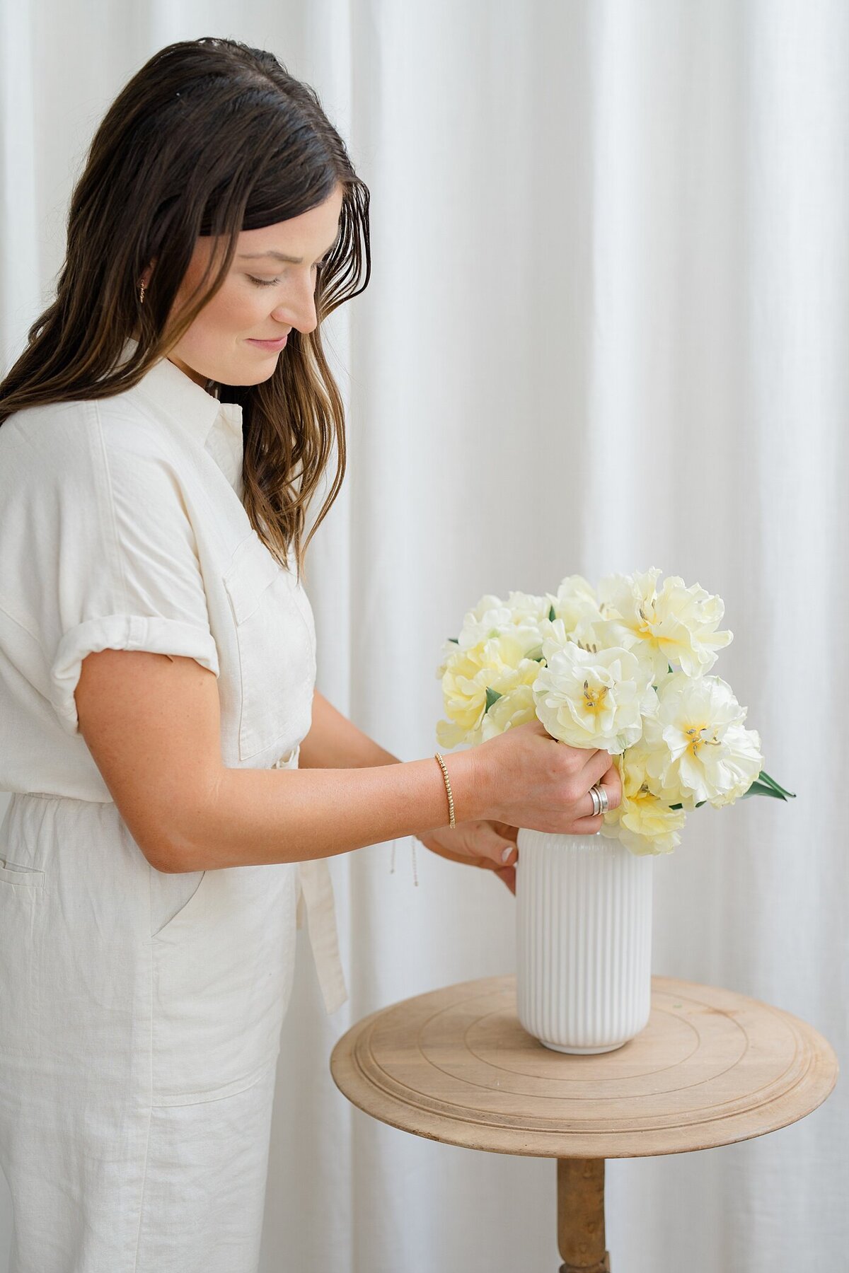 Columbus photographer captures candid picture of a florist arranging cream flowers in a white vase for branding photography