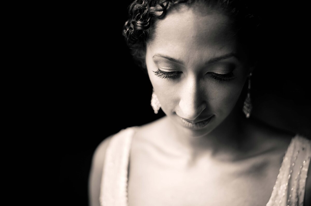 A black and white portrait of a women looking down with dramatic light