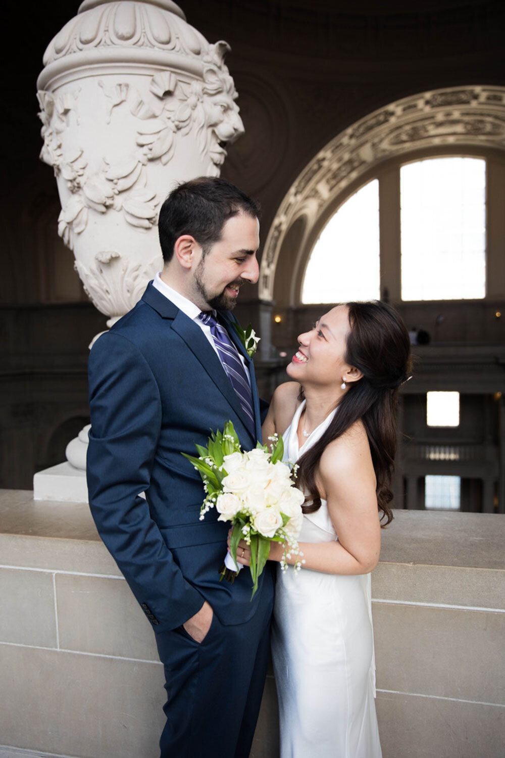 Happy couple embracing with a simple white bouquet indoors
