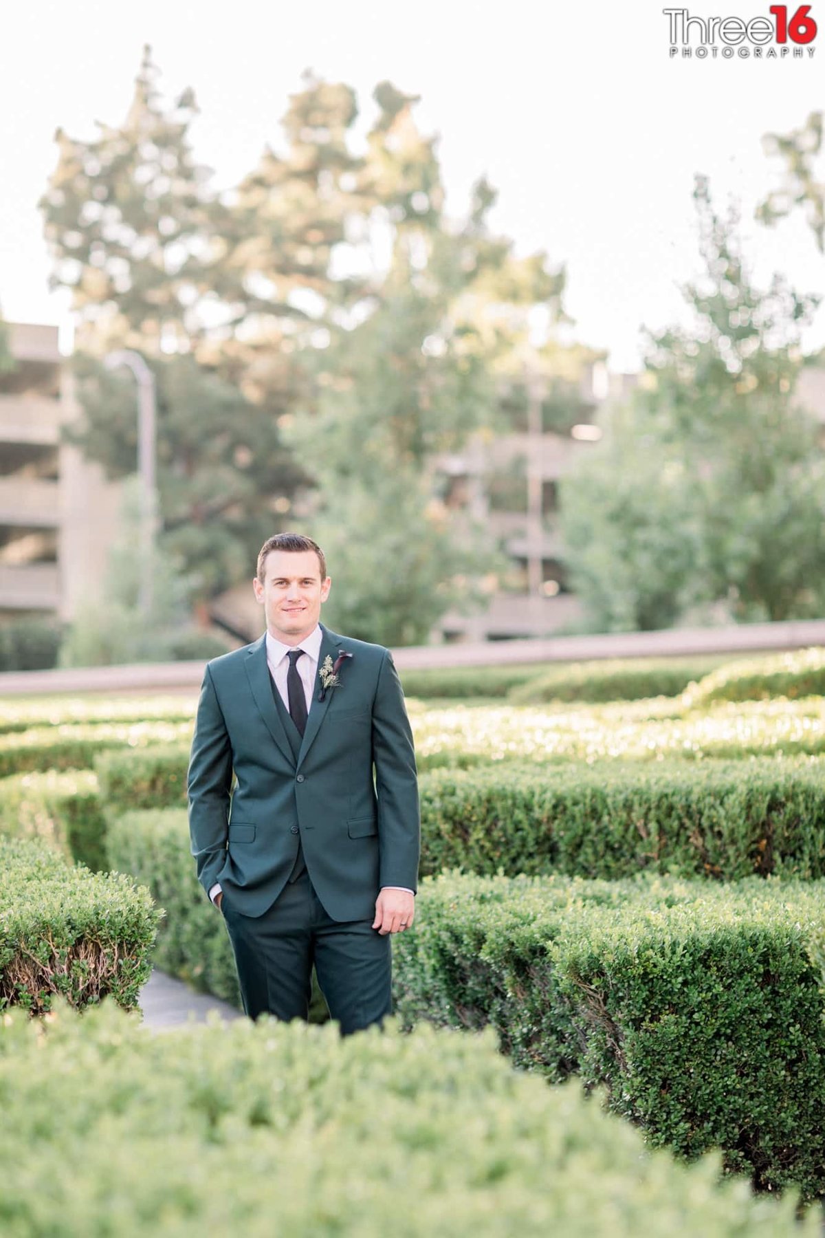 Groom poses for photos amongst the bushes at the Center Club in Costa Mesa, CA