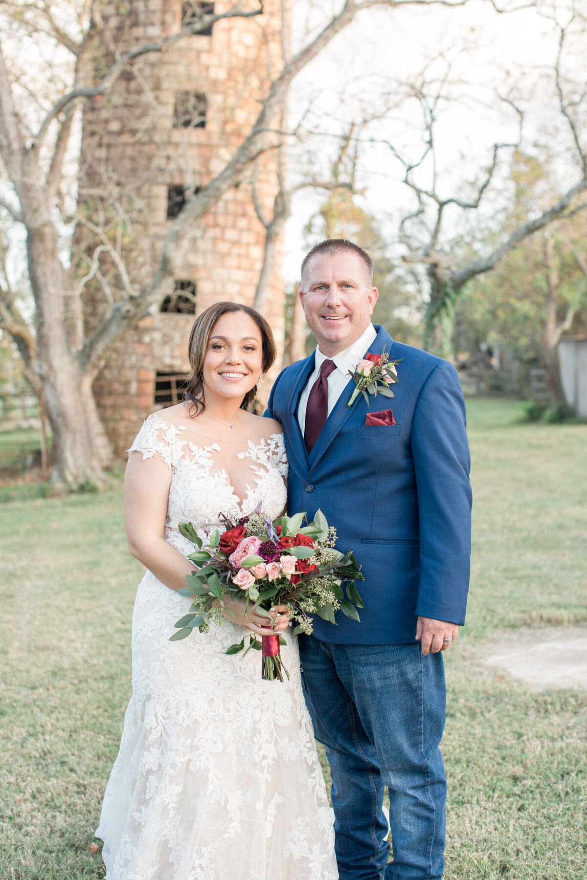 The bride & groom smile for the camera in front of an old silo