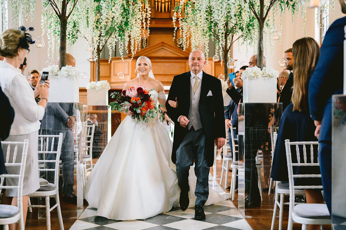 father of bride wals bride down the aisle in the wedding ceremony