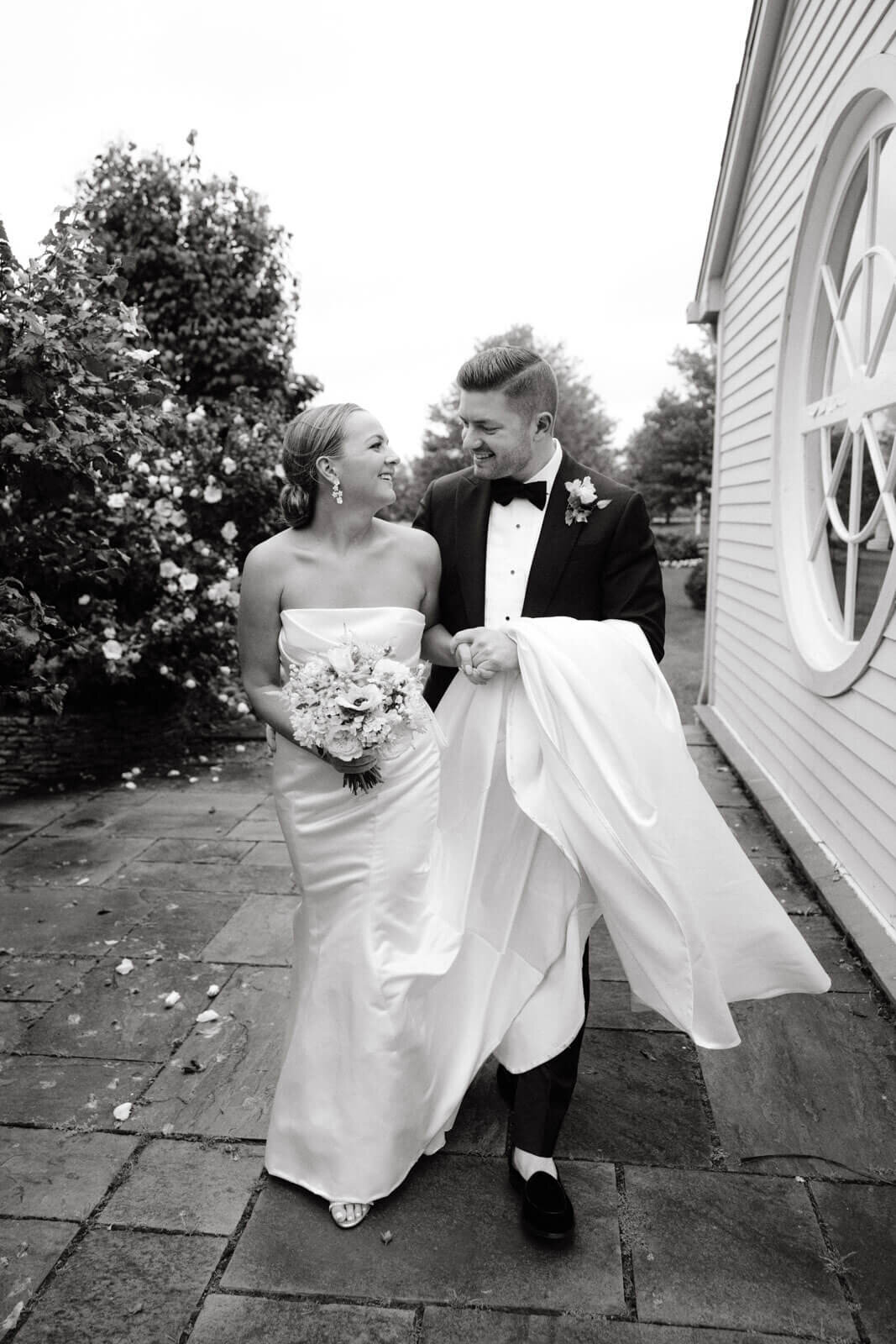 The bride and the groom are happily walking in a beautiful garden at The Lion Rock Farm, CT. Image by Jenny Fu Studio