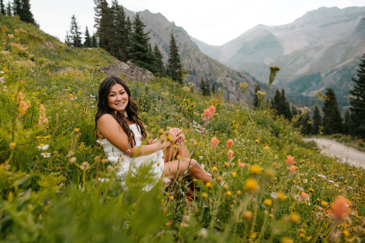 Pragati sits in a field of wildflowers for her Ouray senior pictures.