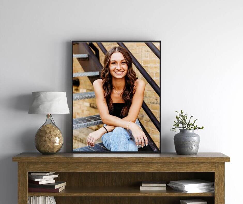 beautiful framed image of a high school senior girl sitting on a wooden entry table next to a lamp and plant in a home near Oshkosh