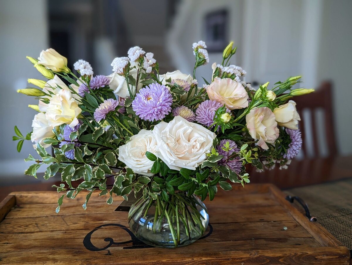 purple and white funeral flower arrangement in vase
