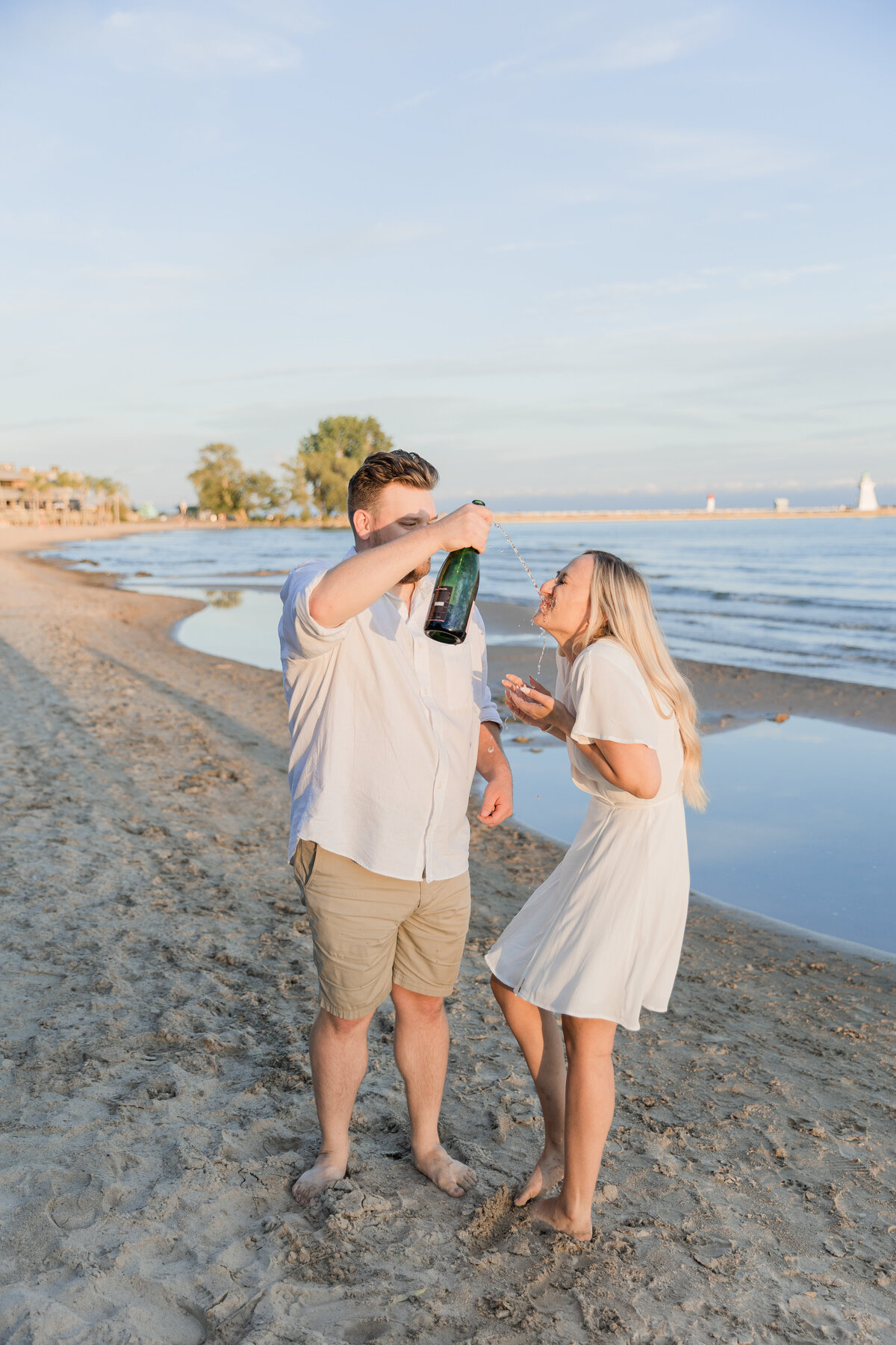 couple laughing and drinking champaign on a beach